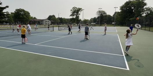 girls and boys playing tennis on a court